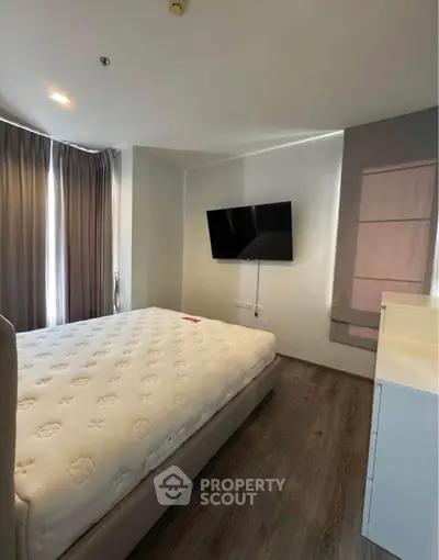 Modern bedroom with sleek design, featuring a wall-mounted TV and large windows for natural light.