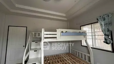 Spacious bedroom with loft bed and ample natural light from large window.