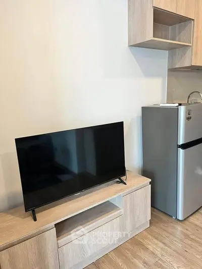 Modern apartment interior with sleek TV and compact fridge in stylish wooden cabinetry.