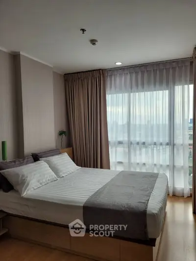 Modern bedroom with large window and elegant decor in a high-rise apartment.