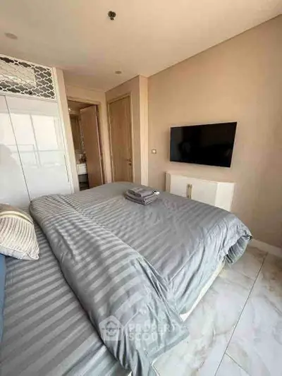 Modern bedroom with stylish decor and wall-mounted TV, featuring a cozy bed and elegant design.