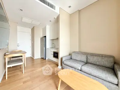 Modern living room with open kitchen, wooden floors, and cozy gray sofa