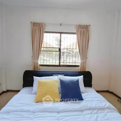 Cozy bedroom with stylish bed and window view, perfect for relaxation and comfort.