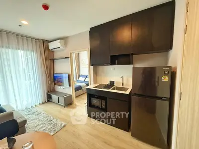 Modern open-layout kitchen with sleek appliances and cozy living area in stylish apartment.