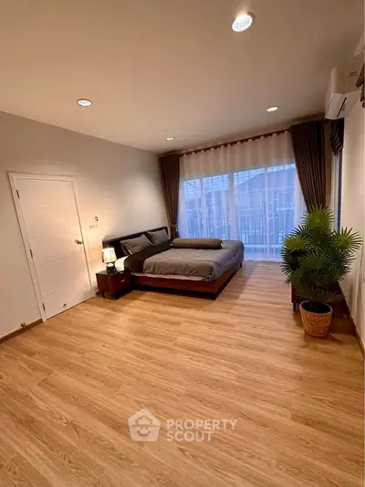 Spacious bedroom with modern decor and large window for natural light.