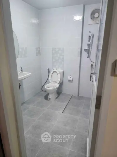 Modern bathroom with sleek fixtures and minimalist design, featuring a shower and toilet.