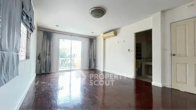 Spacious empty living room with wooden floors and balcony access