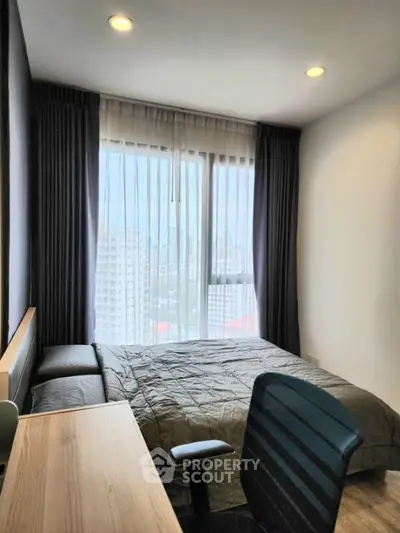 Modern bedroom with city view, featuring a cozy bed and workspace, ideal for urban living.