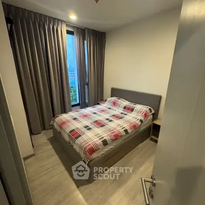Cozy bedroom with modern decor and large window offering natural light.