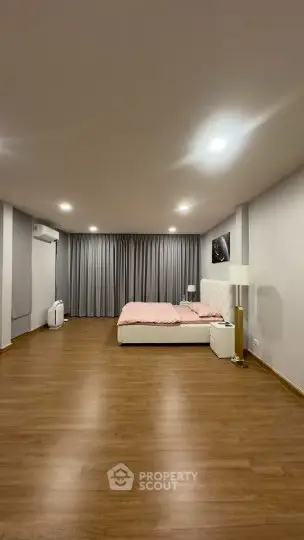 Spacious modern bedroom with wooden flooring and elegant lighting