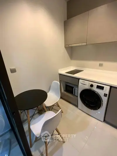Modern compact kitchen with washing machine and dining area, ideal for urban living.