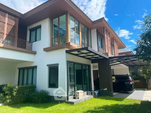 Modern two-story house with large windows and carport in a lush green garden setting.