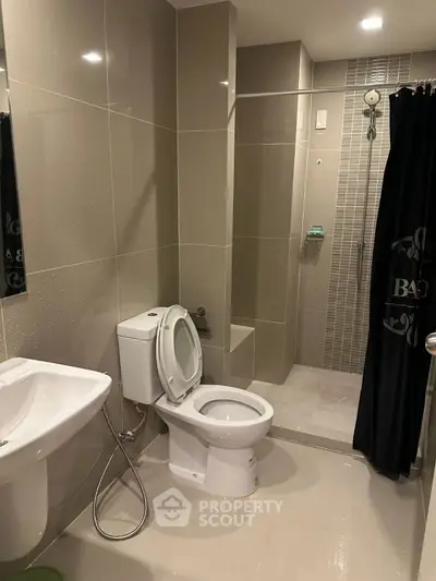 Modern bathroom with sleek design, featuring a shower and toilet in a compact layout.
