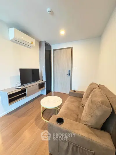 Cozy living room with modern furnishings, featuring a comfortable sofa, wall-mounted TV, and stylish wooden flooring.