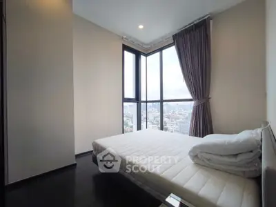 Modern bedroom with panoramic city view and large windows in high-rise apartment.