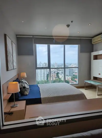 Modern bedroom with large window offering stunning city view, elegant decor, and cozy ambiance.