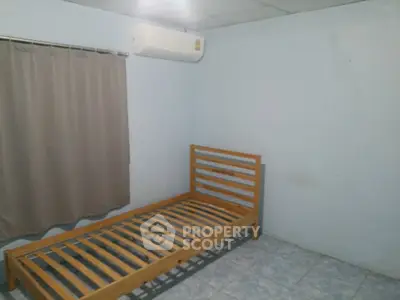Minimalist bedroom with single wooden bed frame and air conditioning unit.