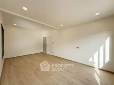 Spacious empty room with wooden flooring and natural light