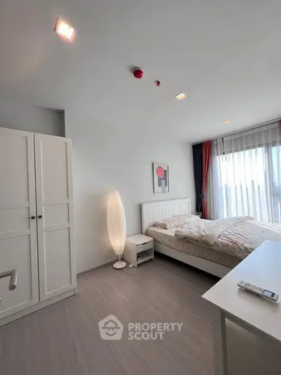 Modern bedroom with natural light, stylish decor, and cozy ambiance in a contemporary apartment.