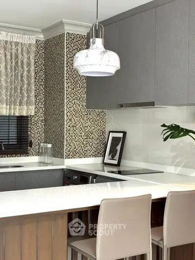 Modern kitchen with sleek cabinetry, marble pendant light, and stylish backsplash, perfect for contemporary living.
