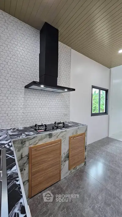 Modern kitchen with sleek marble countertops and gas stove, featuring stylish hexagonal backsplash tiles.