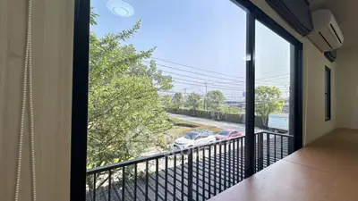 Spacious balcony with serene view of trees and parked cars, perfect for relaxation.