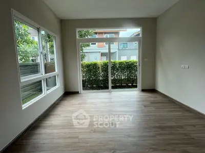 Spacious empty room with large windows and garden view, perfect for customization.