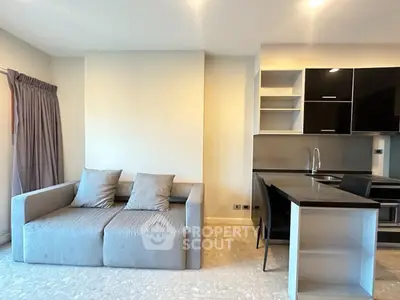 Modern living room with sleek kitchen and cozy sofa in open layout apartment.