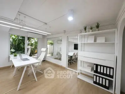 Modern home office with sleek white furniture and large windows overlooking a lush garden.