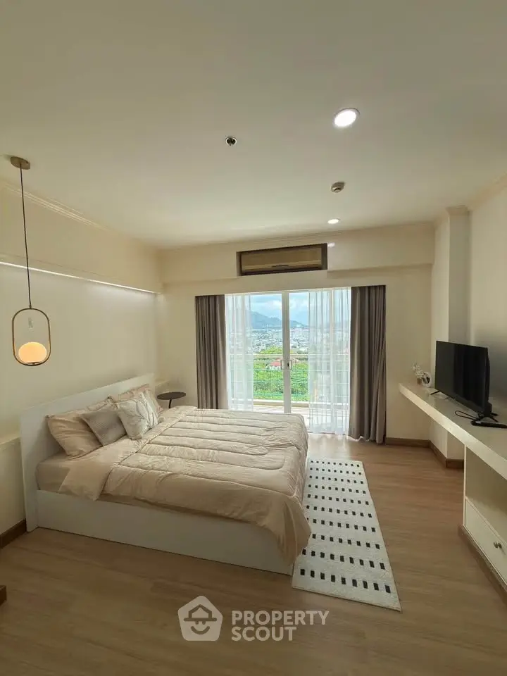 Spacious bedroom with large window offering stunning views, modern decor, and cozy ambiance.