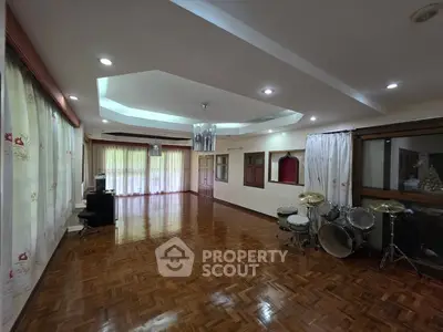 Spacious living room with hardwood floors and drum set, ideal for music enthusiasts.
