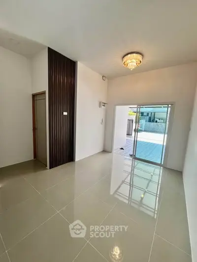 Spacious living room with elegant chandelier and sliding glass doors leading to a patio.