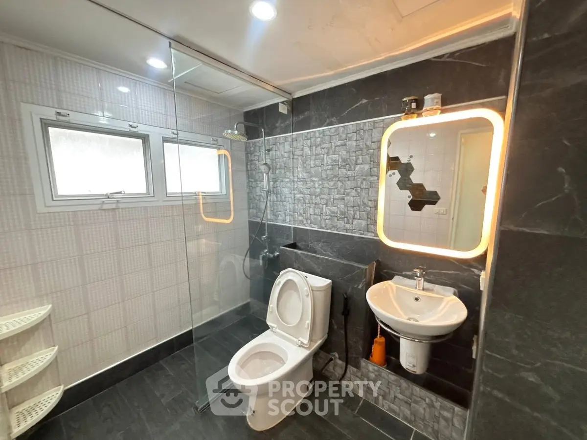 Modern bathroom with sleek design, featuring glass shower enclosure and stylish lighting.