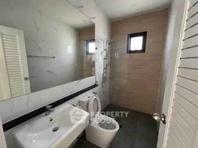 Modern bathroom with sleek fixtures and large mirror, featuring a spacious shower area.