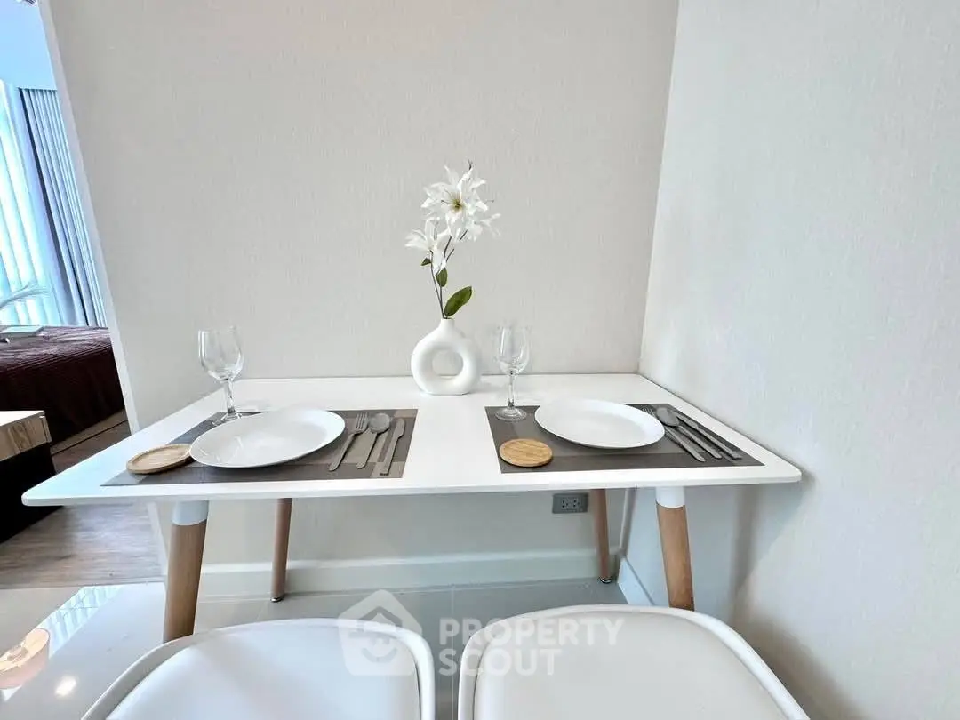 Modern dining area with sleek white table and elegant decor in a stylish apartment.