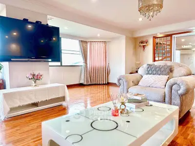 Spacious living room with elegant decor and large TV, perfect for relaxation.