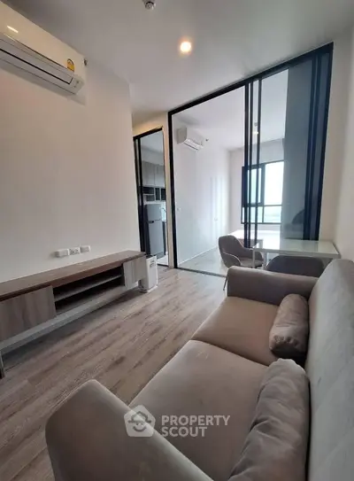 Modern living room with sleek furniture and glass partition in a stylish apartment.
