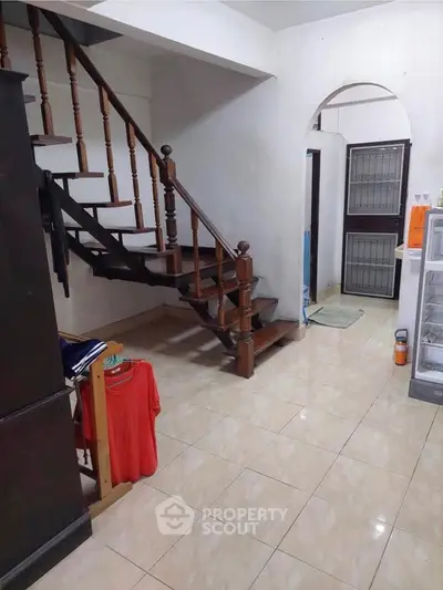 Charming interior with wooden staircase and tiled flooring, ideal for cozy living.