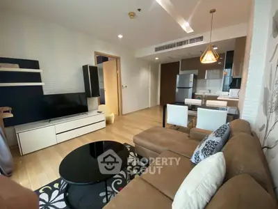 Modern living room with open kitchen, stylish decor, and cozy seating area in a contemporary apartment.