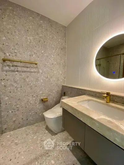 Modern bathroom with terrazzo tiles and illuminated round mirror