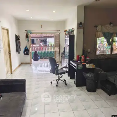 Spacious living room with tiled floor and outdoor view, ideal for family gatherings.