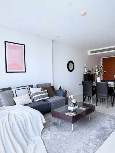 Spacious modern living room with elegant decor and dining area, featuring a cozy sofa and stylish coffee table.