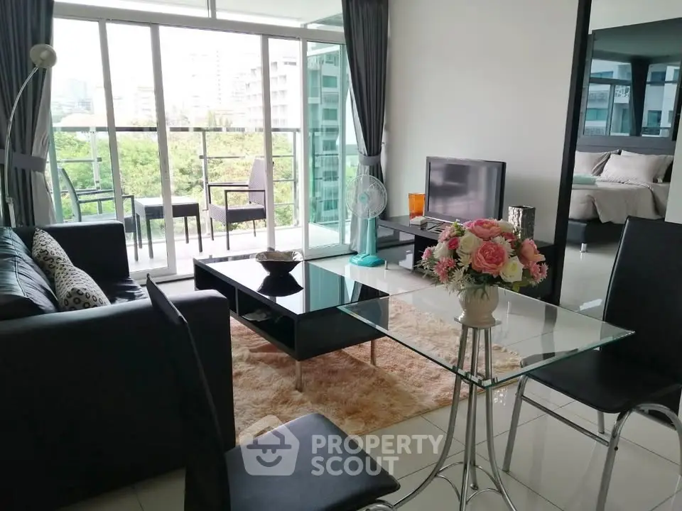 Modern living room with glass table, cozy seating, and balcony view