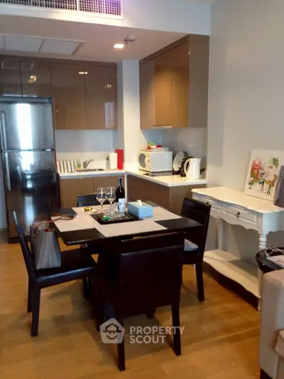 Modern kitchen with dining area, featuring sleek cabinetry and stainless steel appliances.