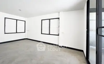Spacious empty room with large windows and modern minimalist design.
