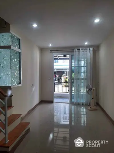 Bright and airy living space with modern staircase and large window view.