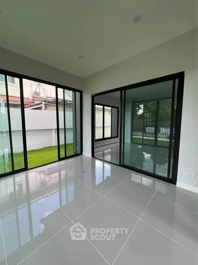 Spacious modern living room with large glass doors and glossy tile flooring