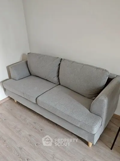 Modern gray sofa in a minimalist living room with wooden flooring, perfect for cozy relaxation.