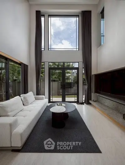 Luxurious high-ceiling living room with large windows and elegant decor