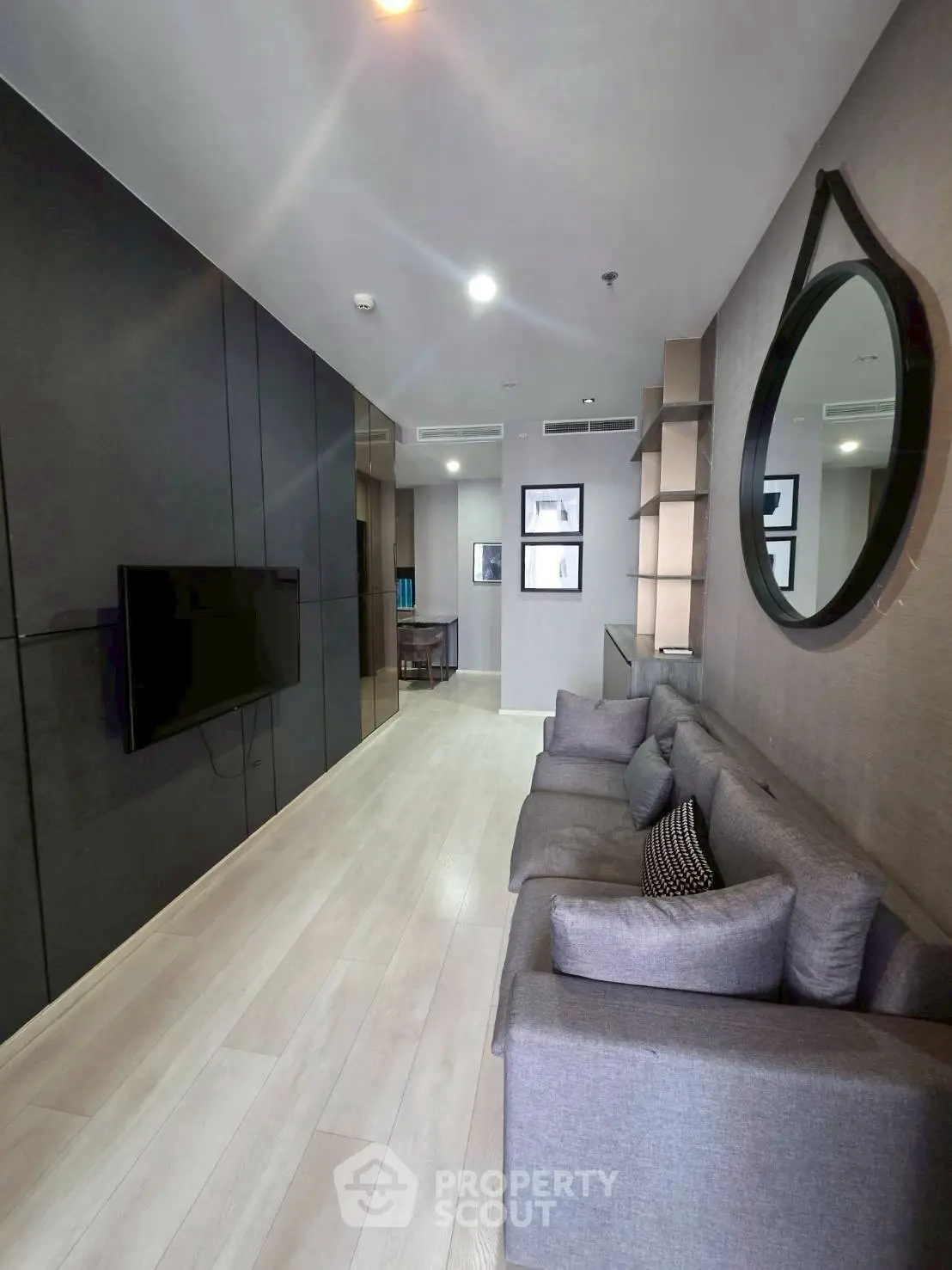 Modern living room with sleek design, featuring a large mirror and comfortable gray sofa.